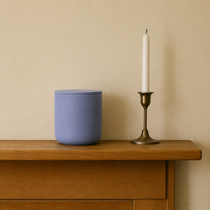 Dusty Blue ceramic keepsake urn displayed on a wooden mantel beside a candle in a home memorial setting
