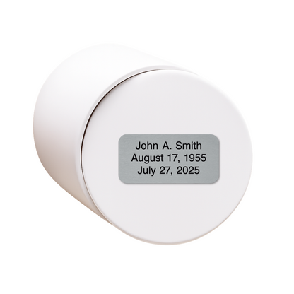White ceramic keepsake urn shown on its side with optional personalized memorial engraving plate